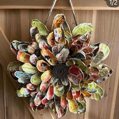 a sunflower made out of seashells hanging from a wooden door with rope