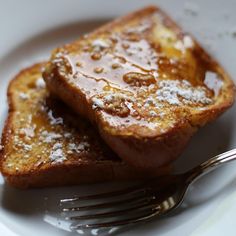 two pieces of french toast with powdered sugar on top and a fork in the foreground