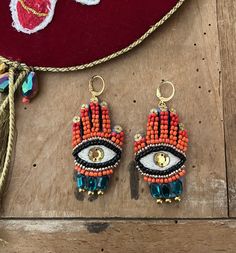 two pairs of beaded earrings on top of a wooden table