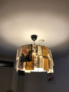 a lamp made out of old books is hanging from the ceiling in a room with white walls