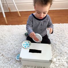 a toddler sitting on the floor playing with a box