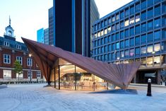 a building with a large triangular roof in the middle of a courtyard area next to tall buildings