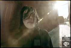 a woman standing in front of a brick wall with the sun shining through her hair