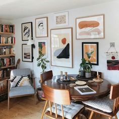 a dining room table with chairs and pictures on the wall above it in front of bookshelves