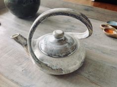 an old tea kettle sitting on top of a wooden table