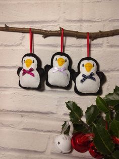 three felt penguin ornaments hanging on a branch