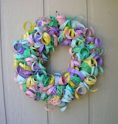 a multicolored wreath hanging on a door with ribbon attached to the front and side