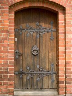 an old wooden door with iron work on the front and side panels, in a brick building