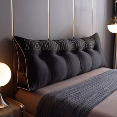 a bed that has some pillows on it and a lamp in front of the bed