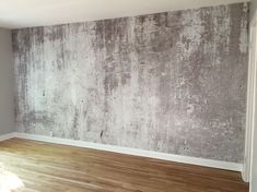 an empty room with wood flooring and concrete wallpaper on the walls, in front of a window