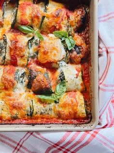 a casserole dish with meat, cheese and spinach on it sitting on a red and white checkered table cloth