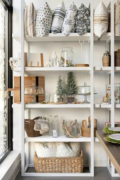 a white shelf filled with lots of dishes and baskets on top of it's shelves