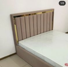 a bed with a white mattress and beige headboard