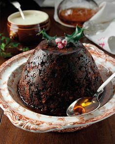 a chocolate cake with holly on top in a bowl and spoon next to the plate