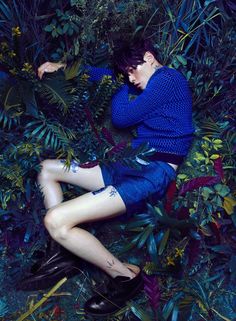 a woman laying on the ground surrounded by plants