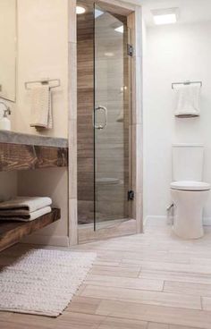 a bathroom with a glass shower door and wooden shelves on the wall next to it