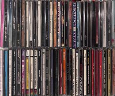 a collection of various cd's are stacked on top of each other in a rack