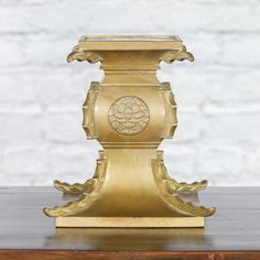 a gold vase sitting on top of a wooden table