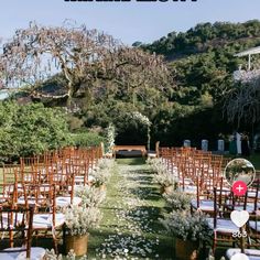 an outdoor ceremony setup with wooden chairs and white flowers on the aisle, surrounded by greenery