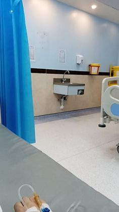 an empty hospital room with blue drapes and medical equipment on the floor in front of it