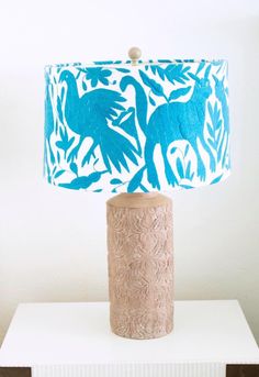 a lamp that is sitting on top of a white table with a blue bird design on it