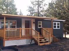 a mobile home with stairs leading to the front porch and second story deck area, surrounded by pine trees