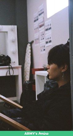 a woman sitting in a chair looking at something on the wall next to her head