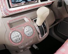 the interior of a car decorated with pink and white beads, including an electronic device