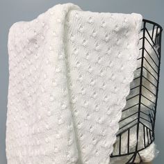 a white knitted blanket sitting on top of a metal rack