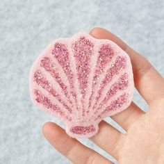 a hand holding a pink glittered scallop