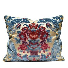 a blue and red pillow with an ornate design on the front, sitting on a white surface