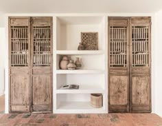 an open bookcase with wooden doors and baskets on the shelves in front of it