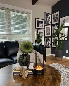 a living room with black leather couches and pictures on the wall above it's coffee table