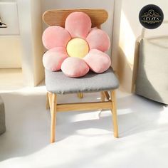 a pink flower sitting on top of a wooden chair next to a white wall and floor