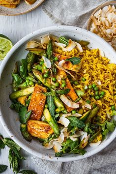 a white bowl filled with rice and vegetables next to other food on top of a table