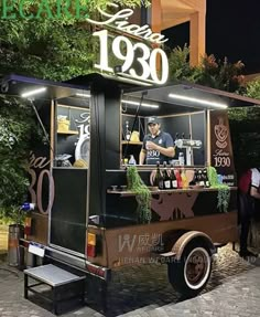 a food truck parked on the side of a street at night with people standing around it