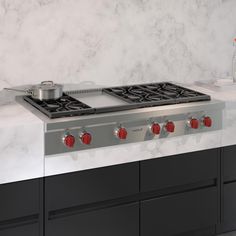 a stove top oven sitting inside of a kitchen next to a counter with red knobs