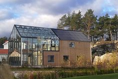 a house made out of wood and glass on the side of a hill with trees in the background