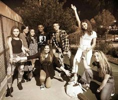 a group of young people standing next to each other in front of a chain link fence