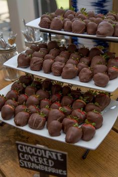 chocolate covered strawberries are displayed on three tiered trays at the dessert table