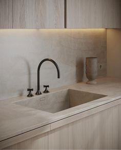 a kitchen sink with two faucets on the side and a vase next to it