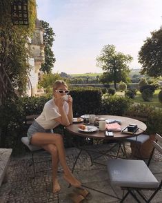 a woman sitting at a table drinking coffee