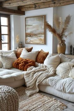 a living room filled with lots of pillows and blankets on top of a white couch