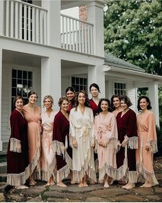 a group of women standing next to each other in front of a house