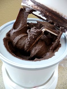 a white bowl filled with chocolate frosting on top of a counter