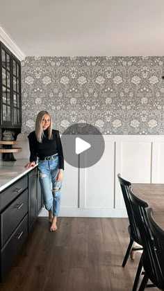 a woman standing in the middle of a kitchen next to a dining room table and chairs