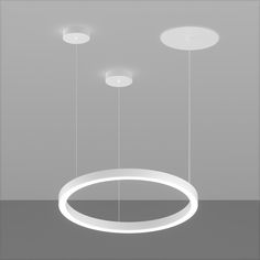 three circular lights suspended from the ceiling in an empty room with grey walls and flooring