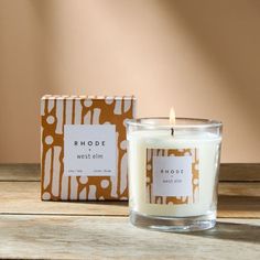 a candle sitting on top of a wooden table next to a brown and white box