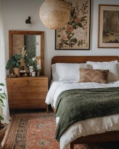 a bed sitting in a bedroom next to a wooden dresser and mirror on top of a rug