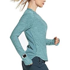 a woman running with her hair blowing in the wind while wearing a blue shirt and leggings